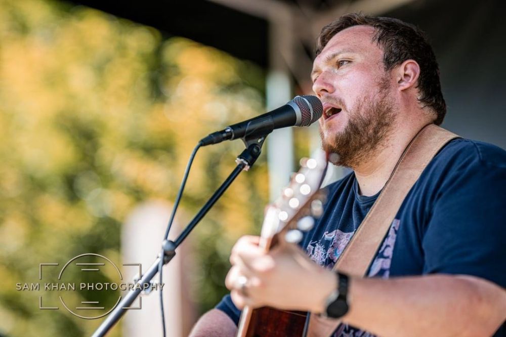 Charlie Cooper sings at a microphone. Credit Sam Khan