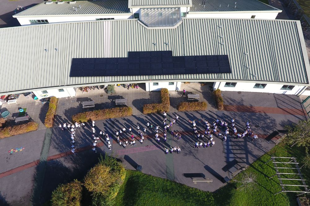 Picture of Barns Green Primary school children organised into a Thank you, viewed from above the school, allowing the new solar panels to be seen 