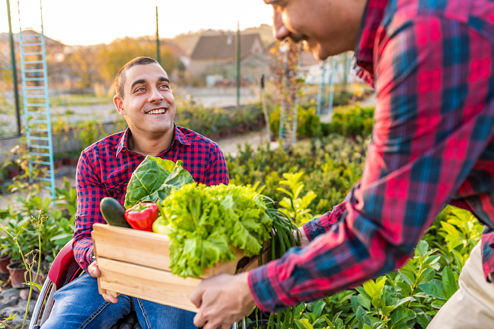 A man smiling holding a box of vegetables