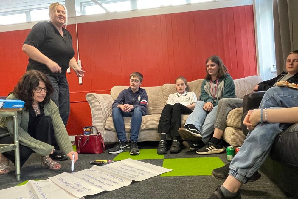 A group of young people working together in a comfortable youth club space