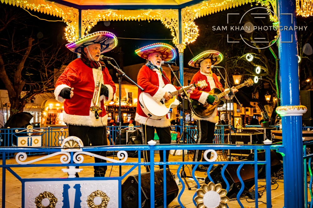 Image of three Mariachi performers with light up hats performing on a bandstand stage