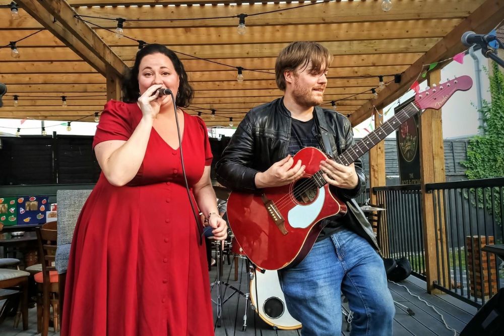 The singer wears a red dress and the guitarist in a leather jacket