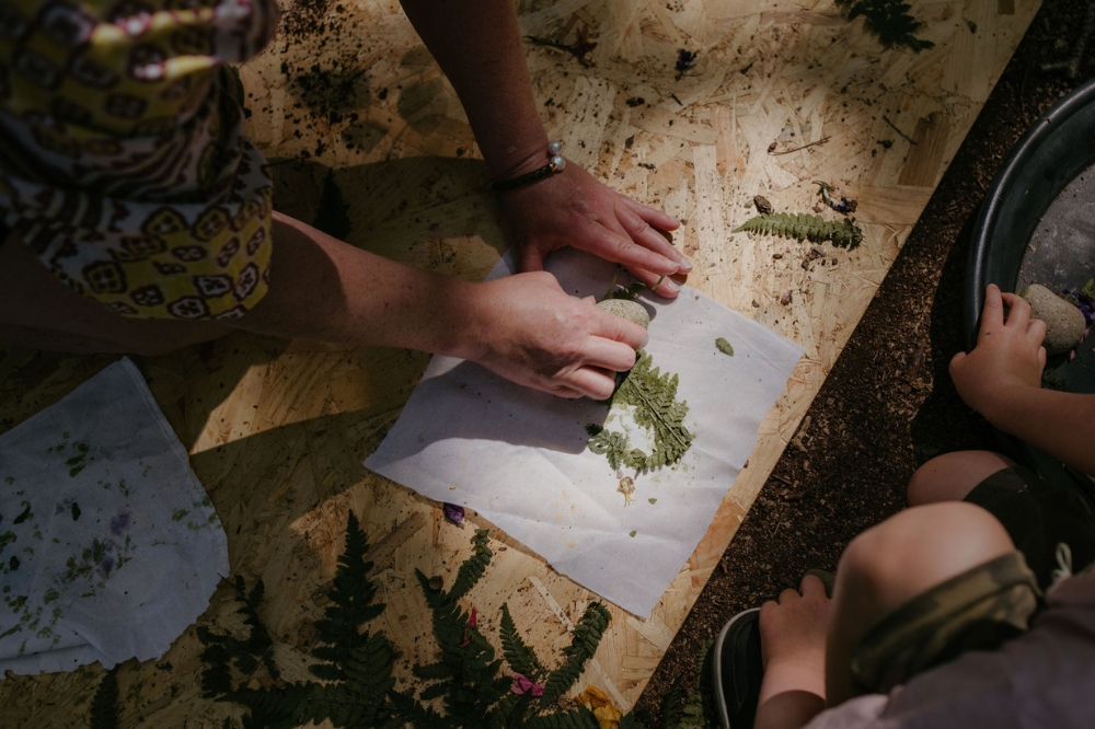 Image taken from a forest school session showing an adult and child exploring fern leaves