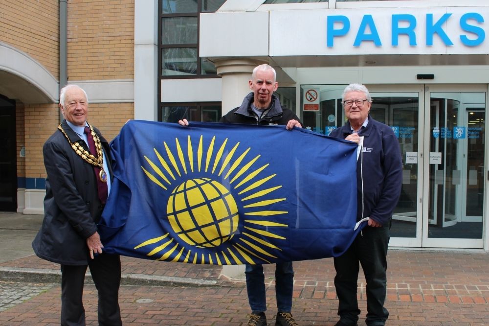 Cllr David Skipp holds the Commonwealth Flag, which is blue and yellow